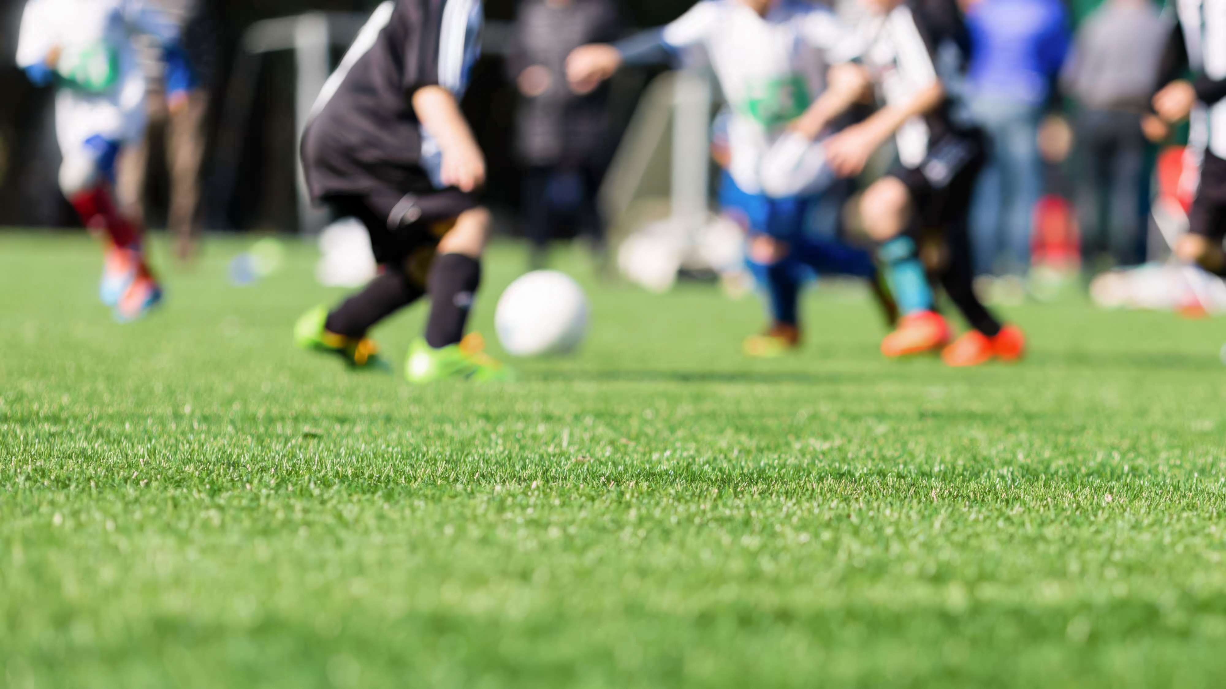 kids playing soccer on green grass